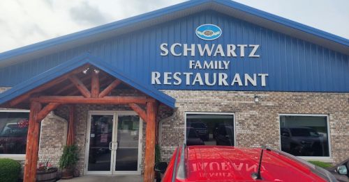 Exterior of Schwartz Family Restaurant, featuring a blue roof, stone walls, and a wooden entrance.