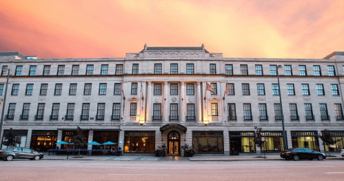 Historic building with a grand facade, illuminated at dusk, set against a colorful sky.