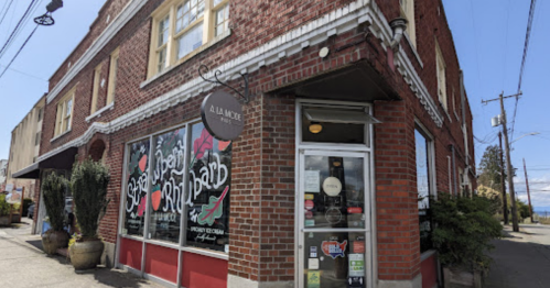 A brick building with large windows displaying colorful signage for a restaurant called "A La Mode."