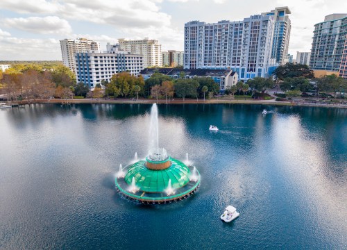 Aerial drone view of the iconic Lake Eola fountain surrounded by downtown Orlando skyline, 2026