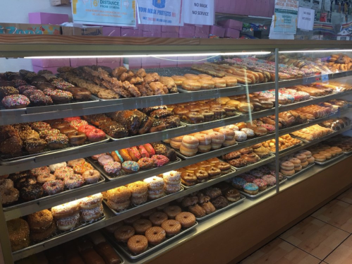 A display case filled with a variety of colorful donuts, including glazed, sprinkled, and frosted options.