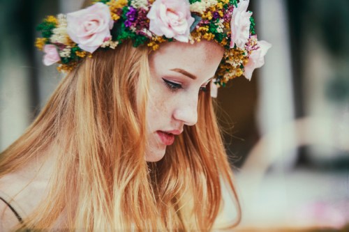 A young woman with long hair and a floral crown gazes thoughtfully to the side, showcasing her profile.