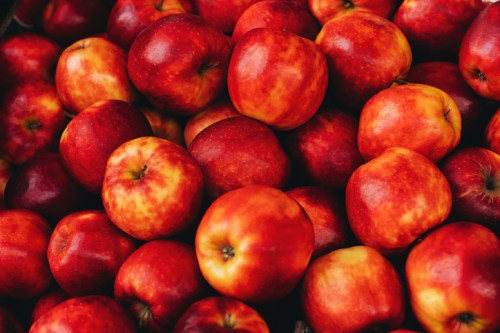 A close-up of a pile of shiny red apples with varying shades of red and yellow.