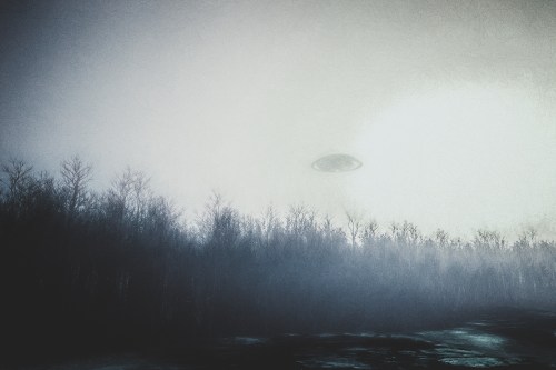 A mysterious UFO hovers above a foggy forest landscape, creating an eerie atmosphere.