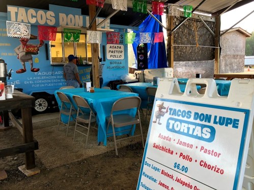 A food truck named "Tacos Don Lupe" with a menu featuring various tacos and tortas, surrounded by colorful decorations.