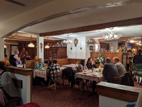 A cozy restaurant scene with diners at wooden tables, warm lighting, and rustic decor, creating a welcoming atmosphere.