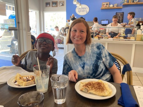 A woman and a child sit at a table in a café, enjoying breakfast with pancakes and an omelet.