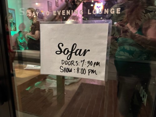 Sign on a window announcing "Sofar" event with details: Doors at 7:30 PM, Show at 8:00 PM.
