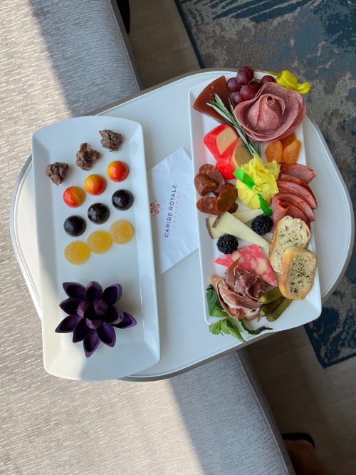 A stylish platter featuring assorted meats, cheeses, fruits, and colorful desserts on a white table.
