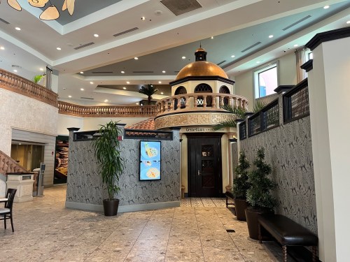 Interior of a spacious lobby featuring a decorative dome, plants, and elegant wall designs.