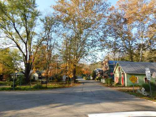 A quaint street scene in autumn, featuring colorful trees and charming buildings under a clear blue sky.