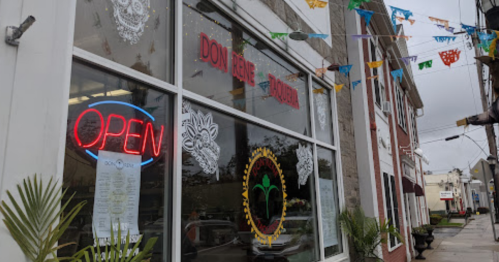 A restaurant window with "OPEN" sign, colorful decorations, and a menu displayed outside.