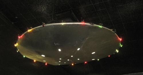 A large, circular metallic object hanging from the ceiling, adorned with colorful lights around its edge.
