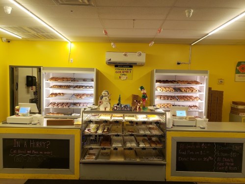 A bright yellow bakery display with various donuts and pastries, featuring a festive Christmas decoration.