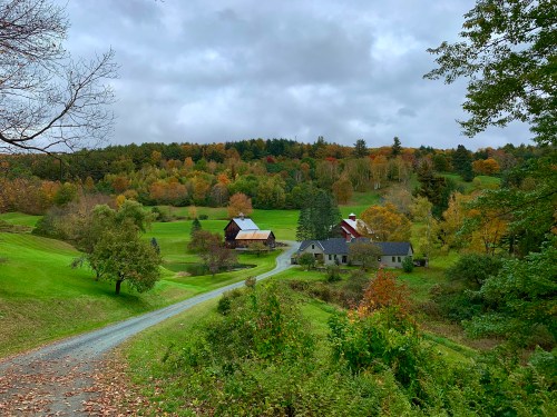 A scenic view of a rural landscape with colorful autumn trees, winding roads, and charming houses.