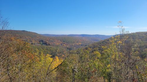 A scenic view of rolling hills covered in autumn foliage under a clear blue sky.