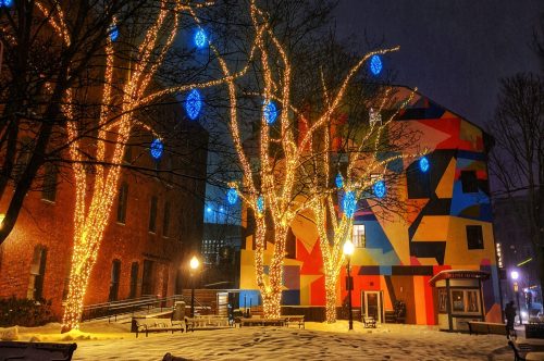 Colorful building with bright blue ornaments and illuminated trees in a snowy park at night.