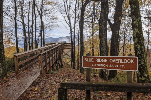 A wooden overlook sign reading "Blue Ridge Overlook, Elevation 3388 ft," surrounded by trees and mountains in the background.