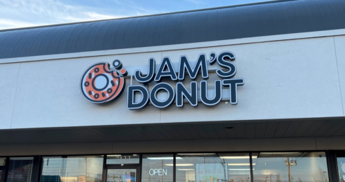 Sign for Jam's Donut, featuring a donut graphic and "OPEN" in the window below.