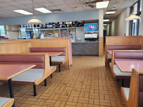 Interior of a fast-food restaurant featuring booths, a counter, and a drink station with Pepsi branding.