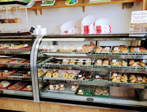A display case filled with various baked goods, including pastries, donuts, and cookies, in a bakery.
