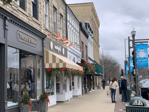 A charming street lined with shops, decorated for the holidays, under a cloudy sky.