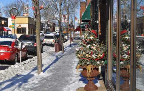 A snowy street scene with holiday decorations, including a festive tree and reflections in shop windows.