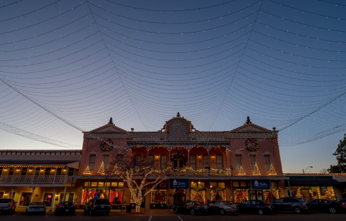 A beautifully lit building adorned with holiday decorations, under a sky filled with twinkling lights at dusk.