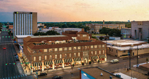 Aerial view of a historic building with outdoor seating, near Baylor University, at sunset with cityscape in the background.