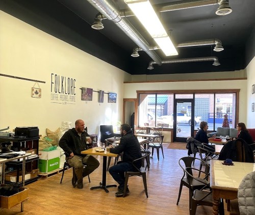 A cozy coffee shop interior with patrons seated at tables, enjoying drinks and conversation.