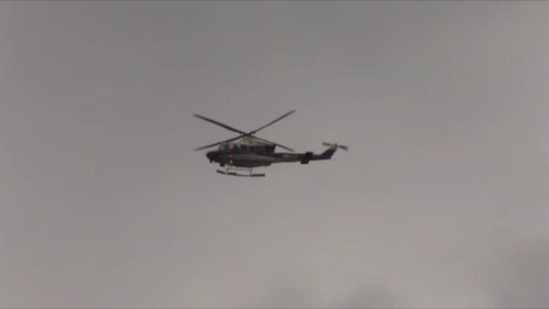 A helicopter flying in a cloudy sky, with its rotor blades spinning.