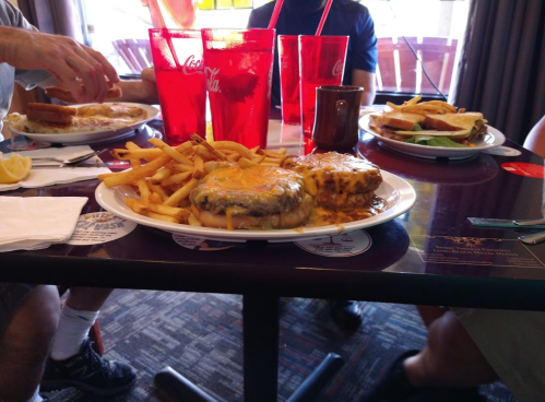 A table with plates of burgers, fries, and drinks in a casual dining setting.