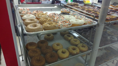 A display case filled with various donuts, including glazed, frosted, and sprinkled varieties.