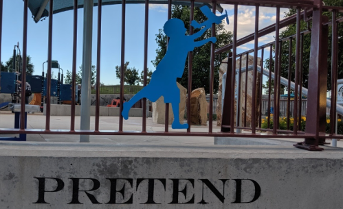 A blue silhouette of a child playing with a toy, next to the word "PRETEND" on a concrete surface.