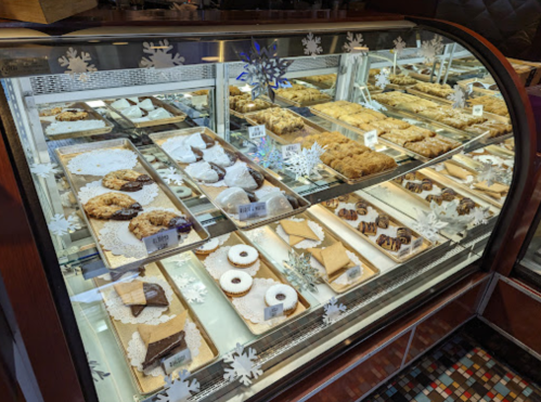 A display case filled with various baked goods, including cookies, pastries, and desserts, decorated with snowflakes.