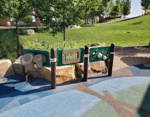 A colorful playground area featuring musical instruments and interactive panels set against a grassy background.