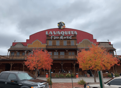 Exterior of La Vaquita Flea Market with autumn trees and a cloudy sky.