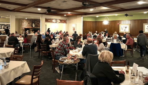 A busy restaurant filled with diners at tables, enjoying meals and conversation in a warm, inviting atmosphere.