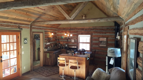 Cozy log cabin kitchen with wooden beams, a central island, and rustic decor, featuring a warm, inviting atmosphere.