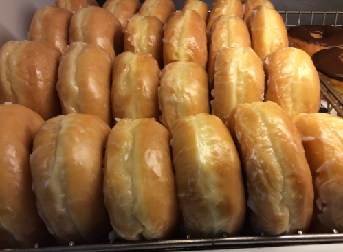 A display of freshly glazed donuts arranged in rows, showcasing their soft, shiny surfaces.