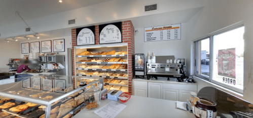 A bakery display case filled with pastries, a coffee machine, and a menu on the wall in a bright, inviting space.