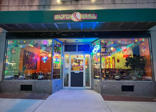 Exterior of Fatta Grill restaurant, featuring colorful lights and an "Open" sign, with a welcoming atmosphere.
