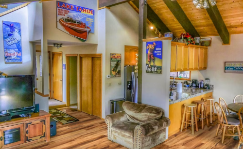 Cozy interior of a Lake Tahoe cabin featuring a living area, kitchen, and vintage posters on the walls.
