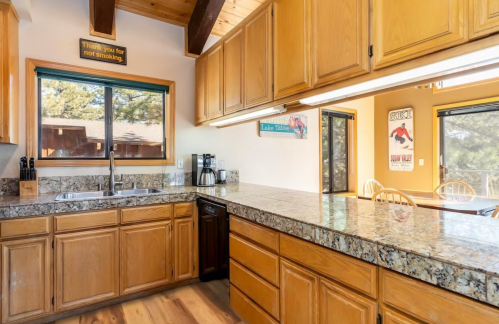 Bright kitchen with wooden cabinets, granite countertops, and large windows overlooking a scenic view.