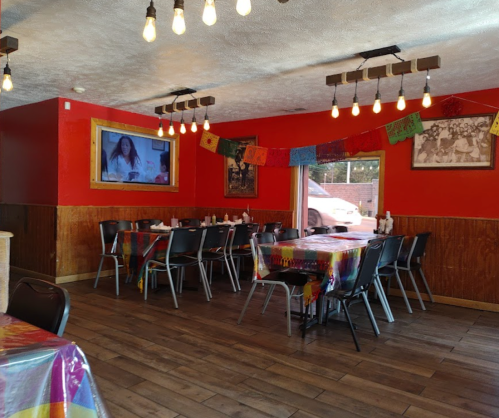 Cozy restaurant interior with colorful tablecloths, string lights, and vibrant wall decor.