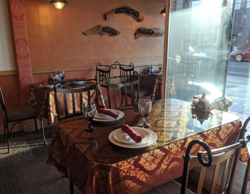 Cozy restaurant interior with elegantly set tables, warm lighting, and decorative wall accents.