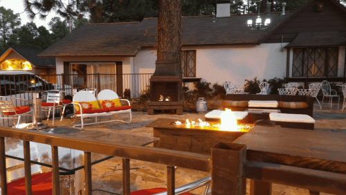 Cozy outdoor seating area with a fire pit, surrounded by trees and a charming cabin in the background.
