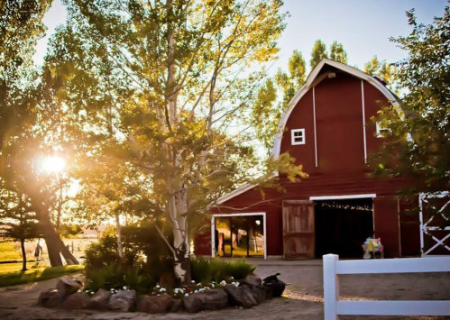 A red barn surrounded by trees and flowers, with sunlight streaming through, creating a warm, inviting atmosphere.