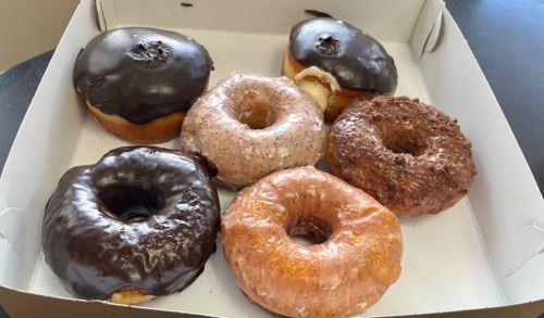 A box of assorted donuts, including chocolate-glazed, glazed, and a frosted variety, arranged neatly.
