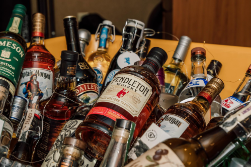 A collection of various liquor bottles, including whiskey, rum, and liqueurs, arranged in a vibrant display.